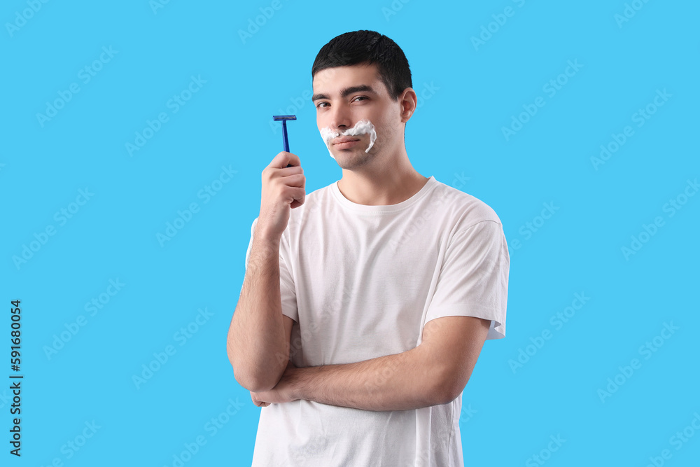 Young man shaving against light blue background