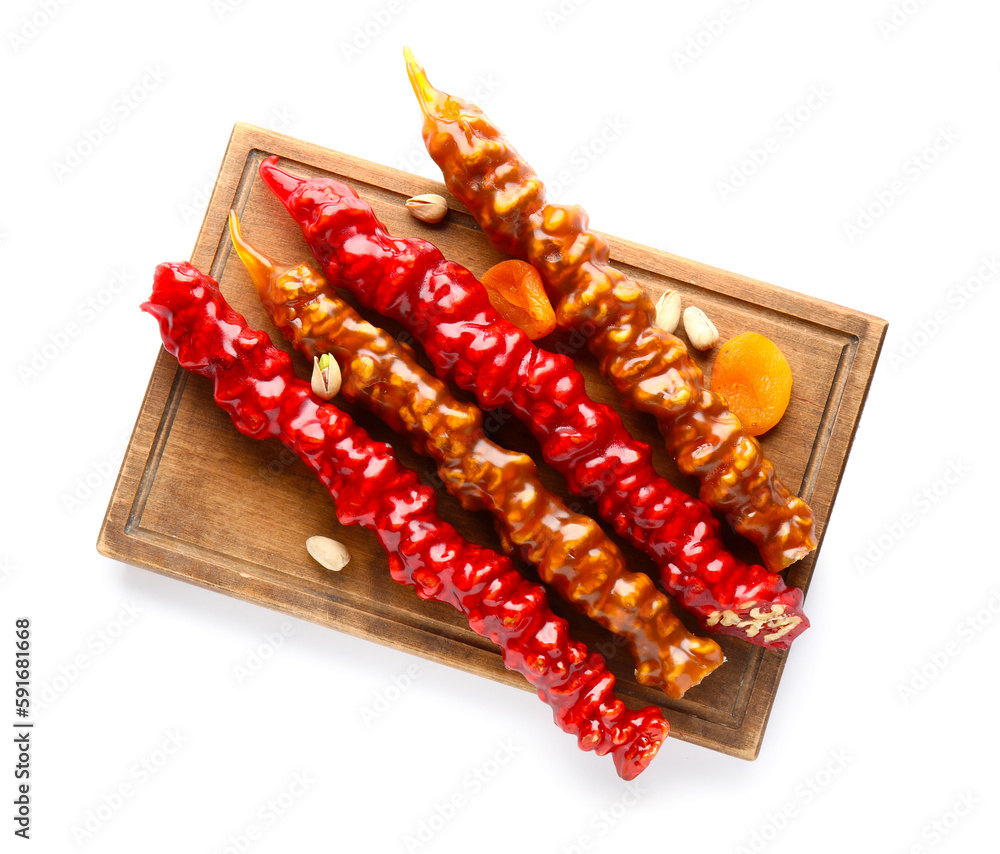 Board with delicious churchkhela, dried apricot and pistachio nuts isolated on white background