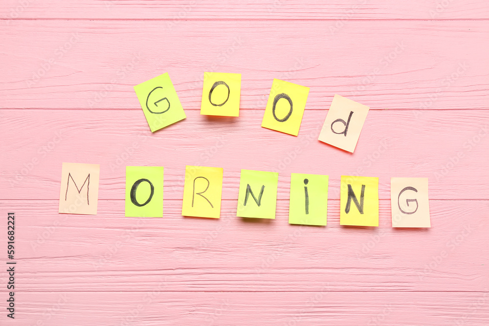 Sticky notes with text GOOD MORNING on pink wooden background