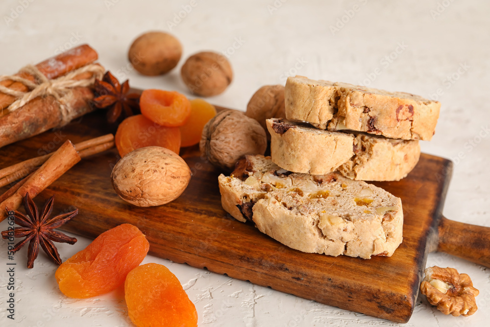 Wooden board with tasty biscotti cookies, walnuts, dried apricots and spices on light background, cl