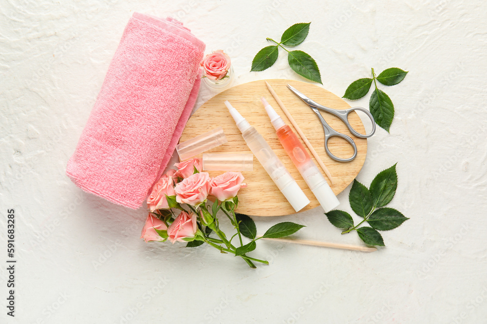 Composition with cuticle oil pens, manicure instruments, towel and rose flowers on light background