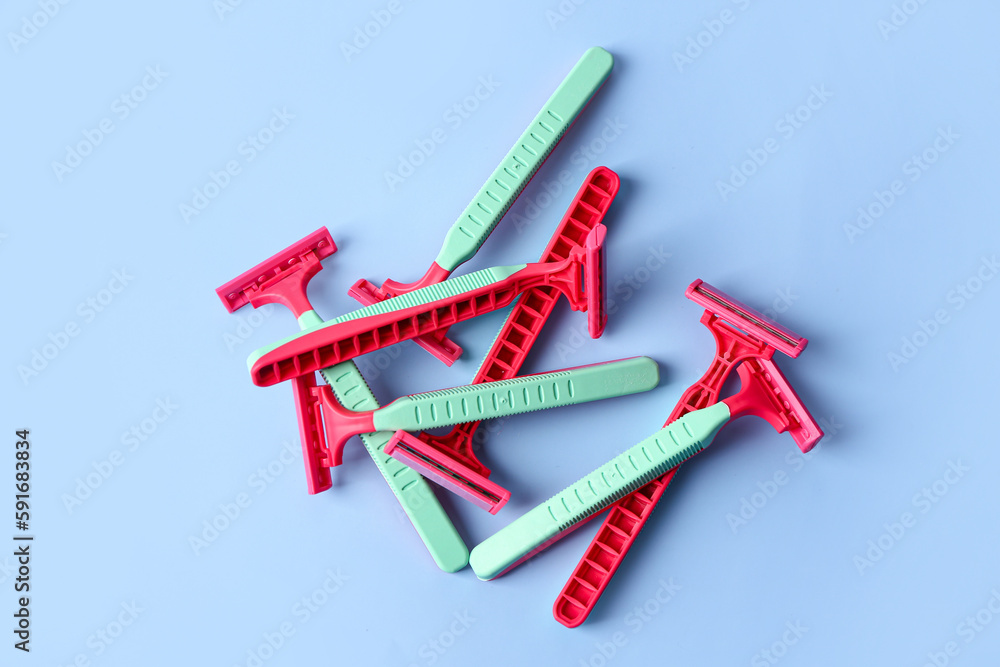 Heap of colorful safety razors on color background