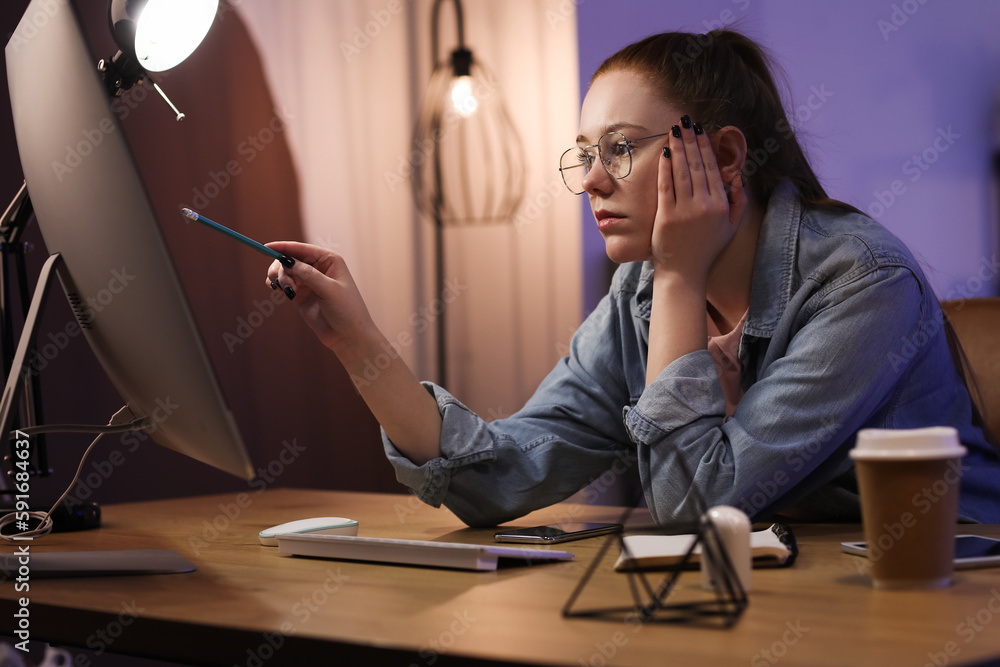 Tired female programmer working with computer in office at night