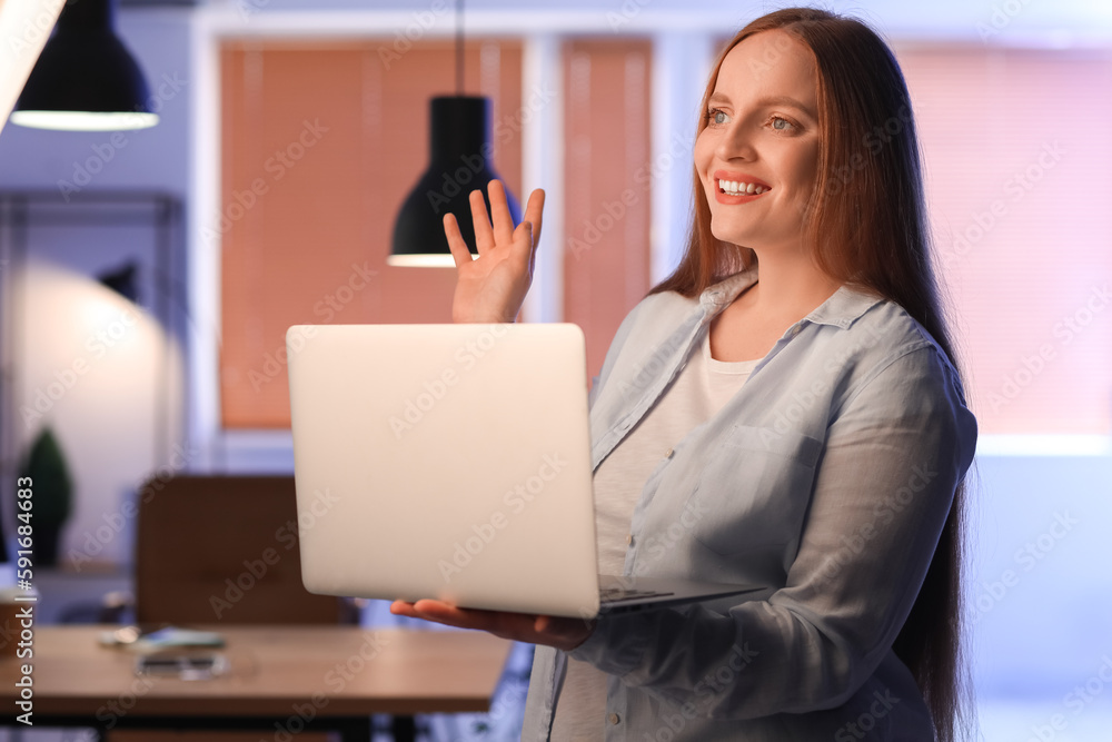 Female programmer working with laptop in office at night