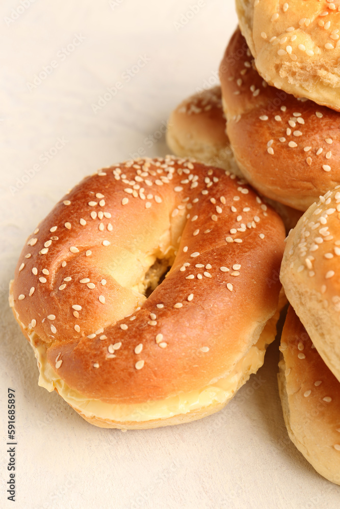 Tasty bagels with sesame and cream cheese on light background, closeup