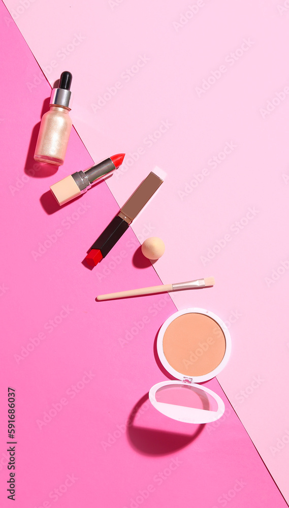 Lipsticks with powder, brush and sponge on pink background