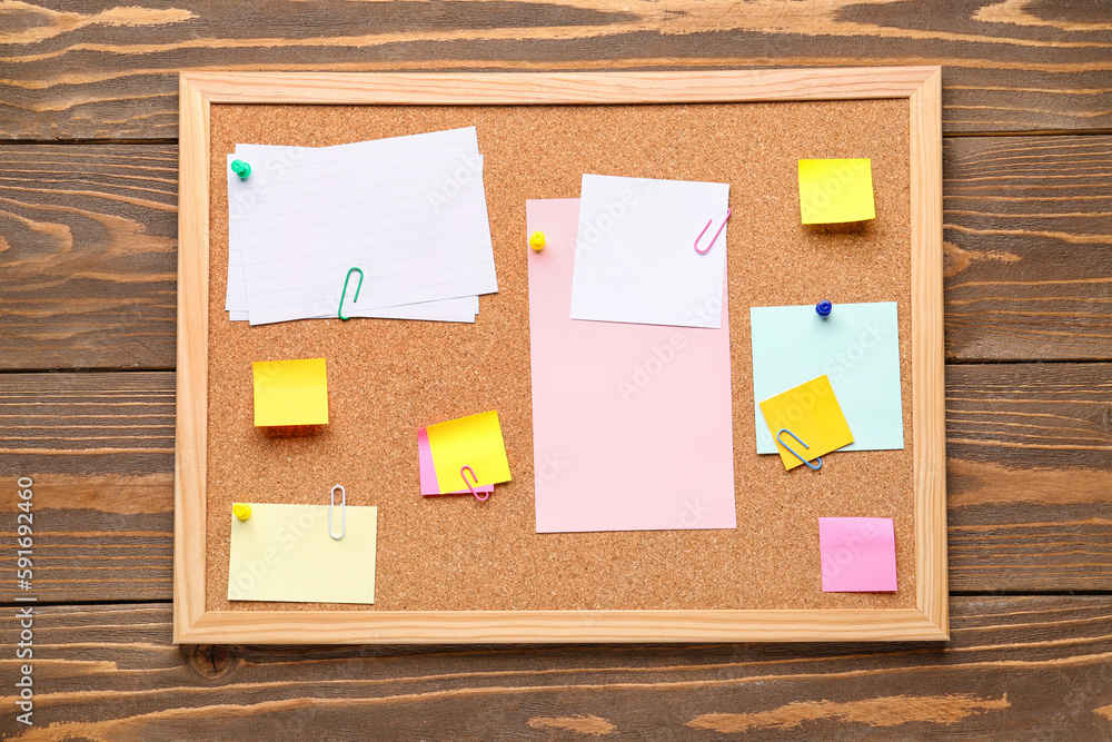 Board with different sticky notes on wooden background