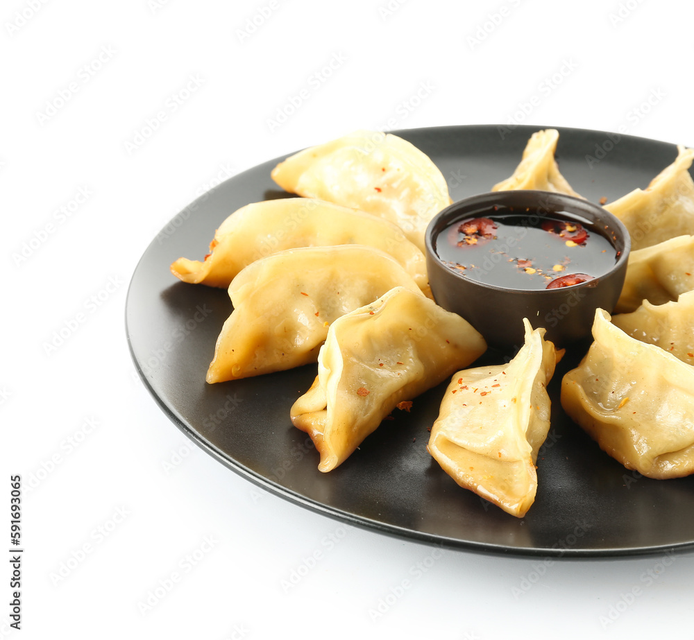 Plate with tasty Chinese jiaozi and sauce on white background