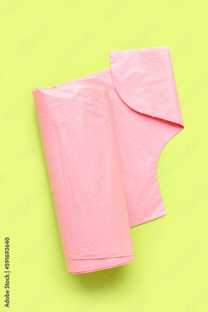 Pink roll of garbage bags on green background