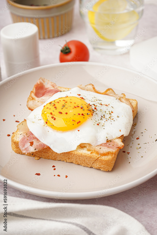 Delicious sandwich with fried egg and bacon on light background