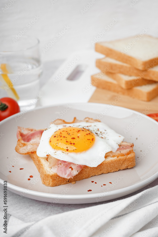 Delicious sandwich with fried egg and bacon on light background