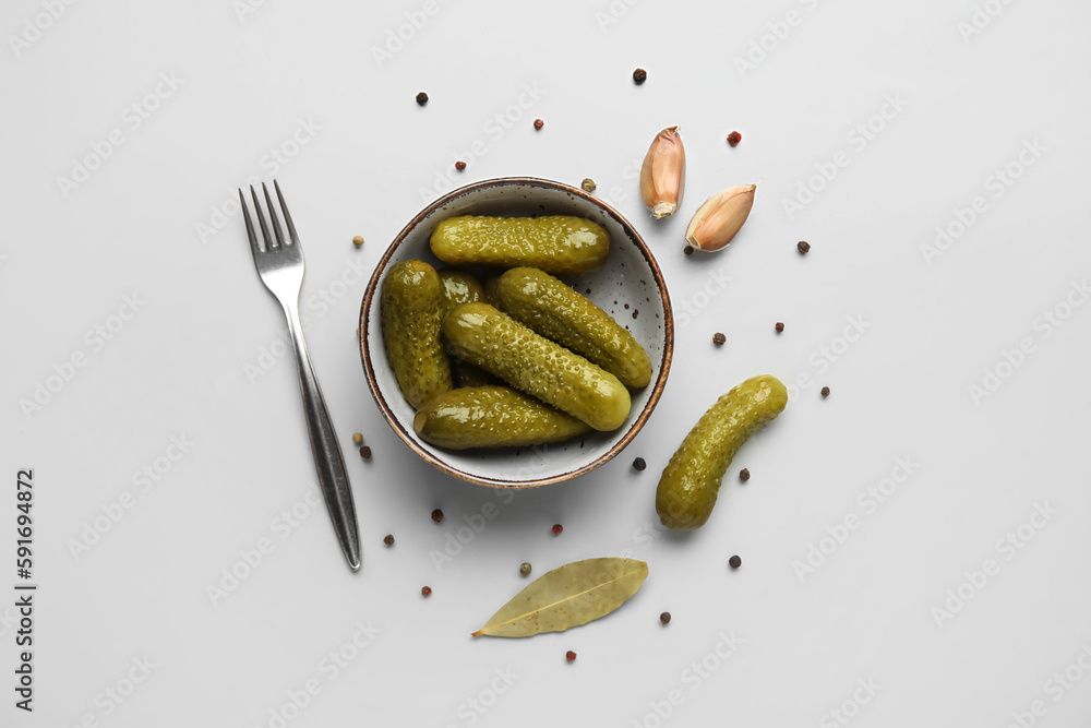 Bowl with tasty fermented cucumbers on light background