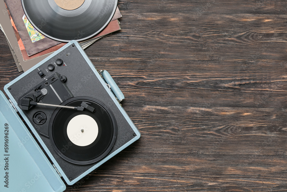 Record player with vinyl disks on dark wooden background