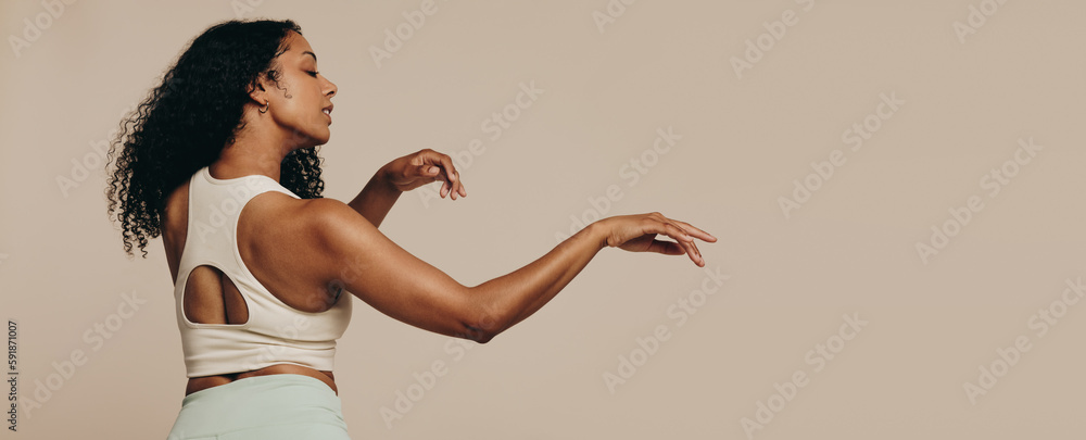 Sporty woman doing an expressive body movement in fitness clothing