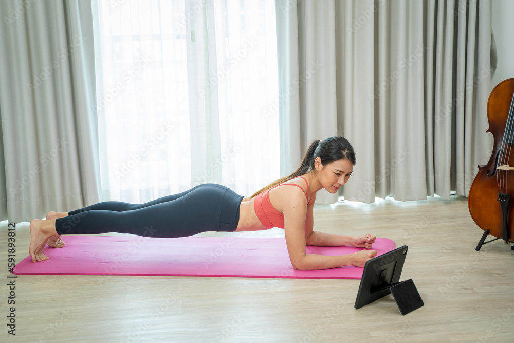 Young woman using tablet pc doing yoga stretching yoga online at home,Entertainment and education on