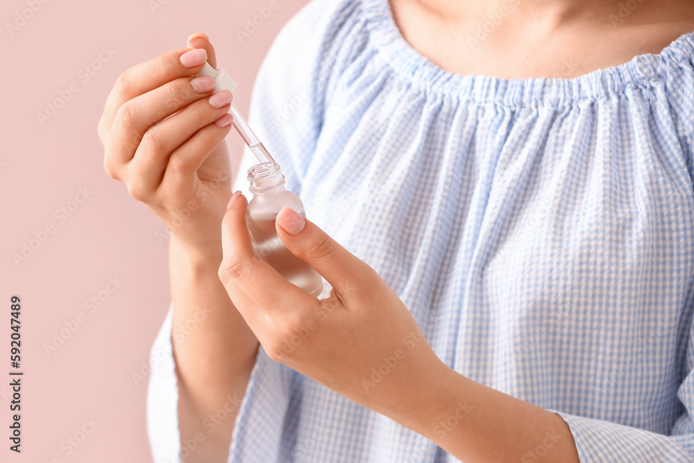 Woman with bottle of cuticle oil near color wall