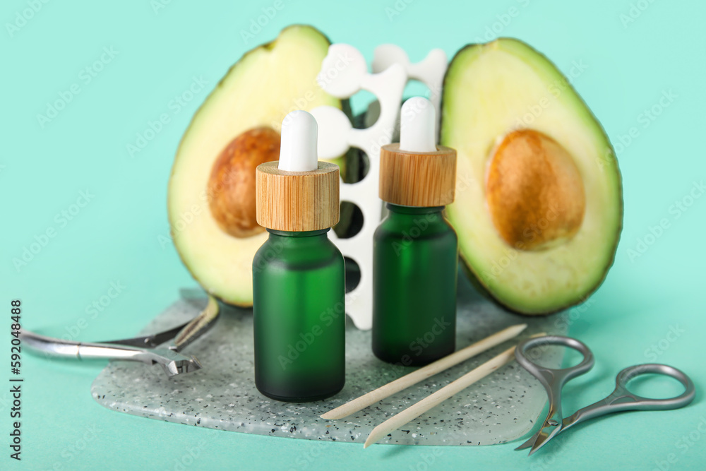 Composition with bottles of cuticle oil, manicure instruments and avocado on color background