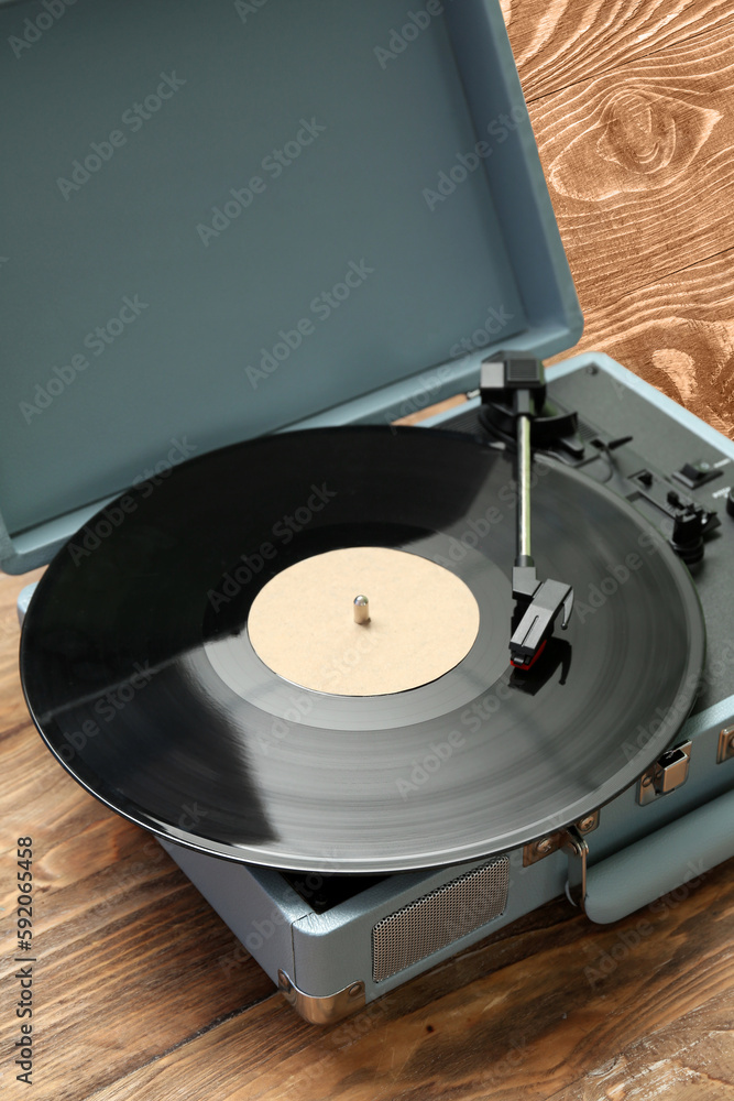 Record player with vinyl disk on wooden background, closeup