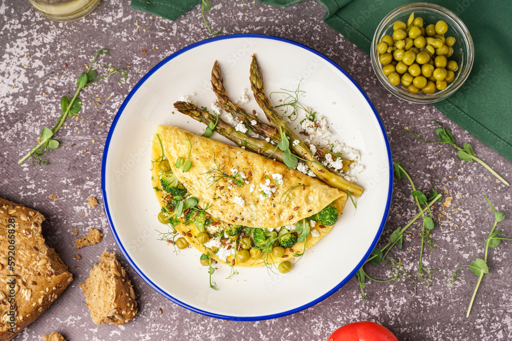 Tasty omelet with broccoli, asparagus and pea on grey background