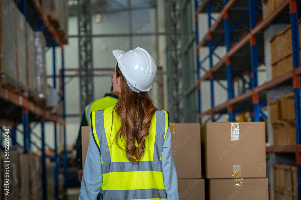 Warehouse worker checking packages on shelf in a large store,Logistics worker storing package boxes.