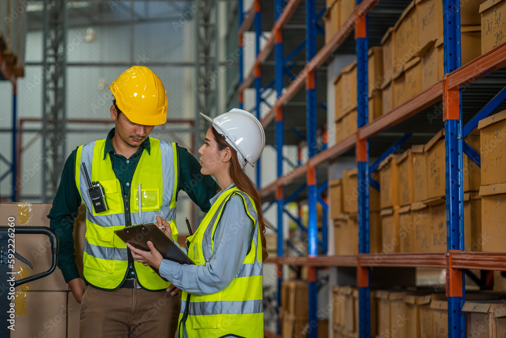 Warehouse worker checking and loading or unloading boxes in a large distribution warehouse.