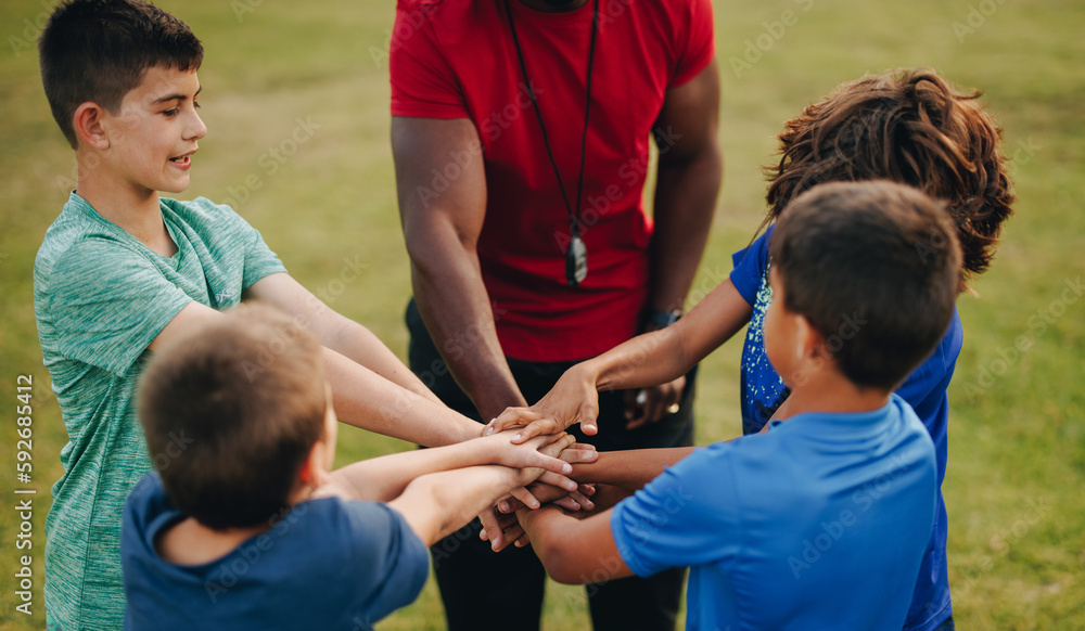 Coach and students putting their hands together in a huddle