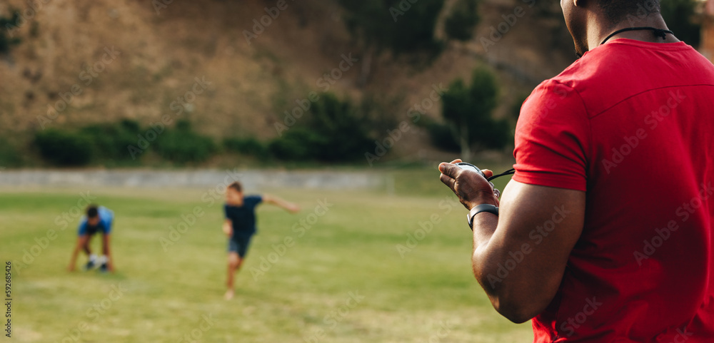 Man coaching school children in a sports ground