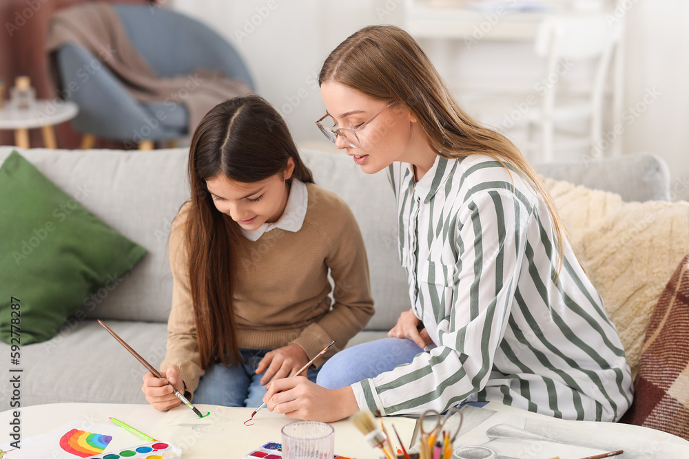 Drawing teacher giving private art lesson to little girl at home