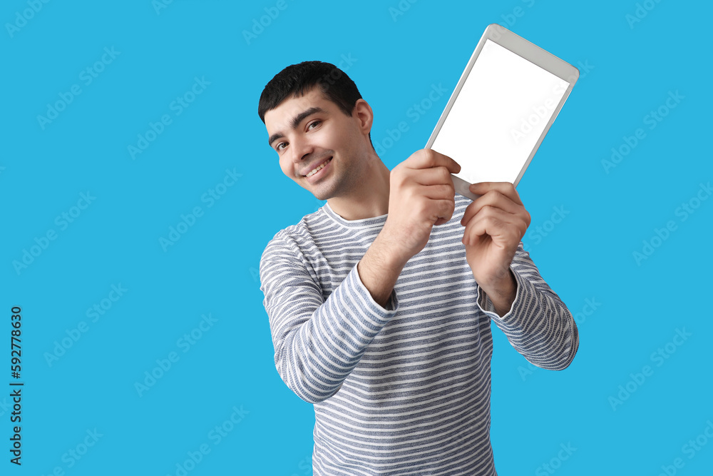 Young man with tablet computer on blue background