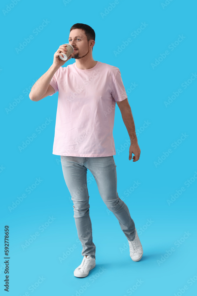 Handsome man drinking coffee on blue background