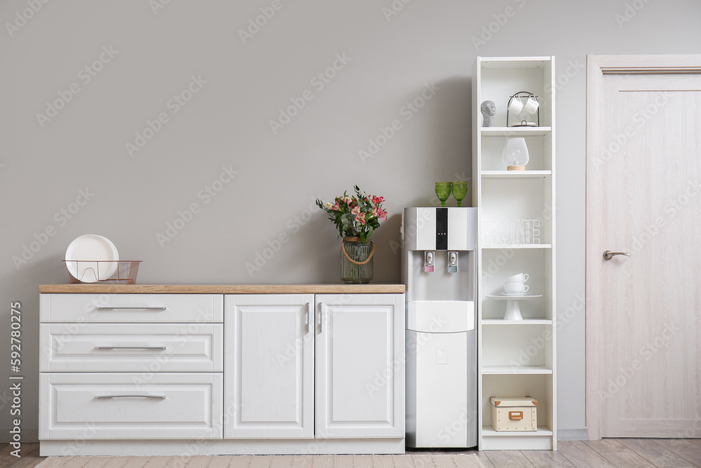 Interior of kitchen with modern water cooler near grey wall