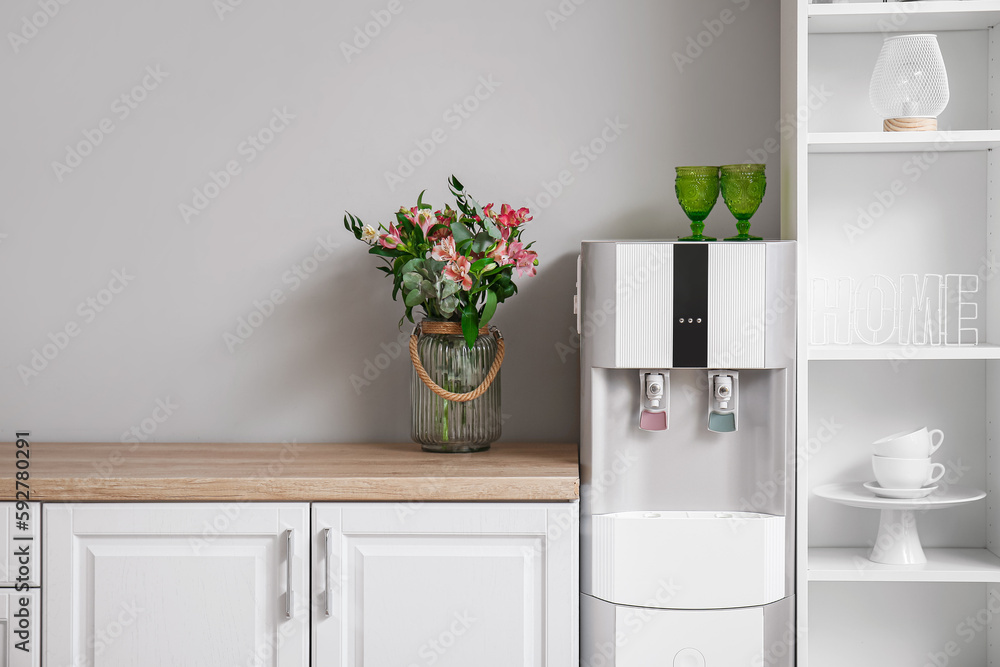 Interior of kitchen with modern water cooler near grey wall