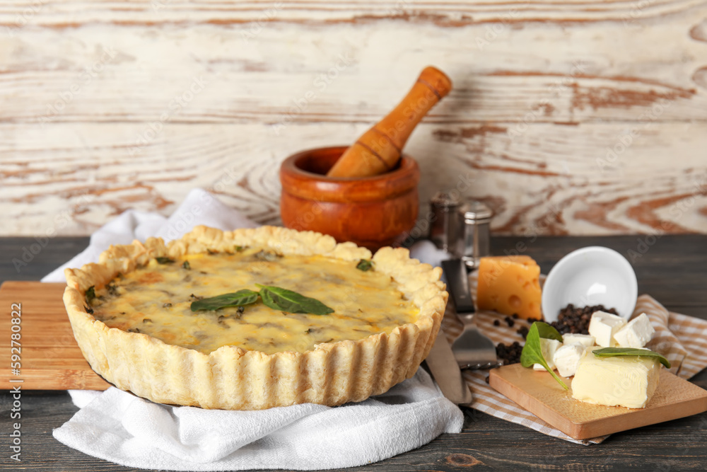 White napkin with delicious quiche on black wooden table near white wall