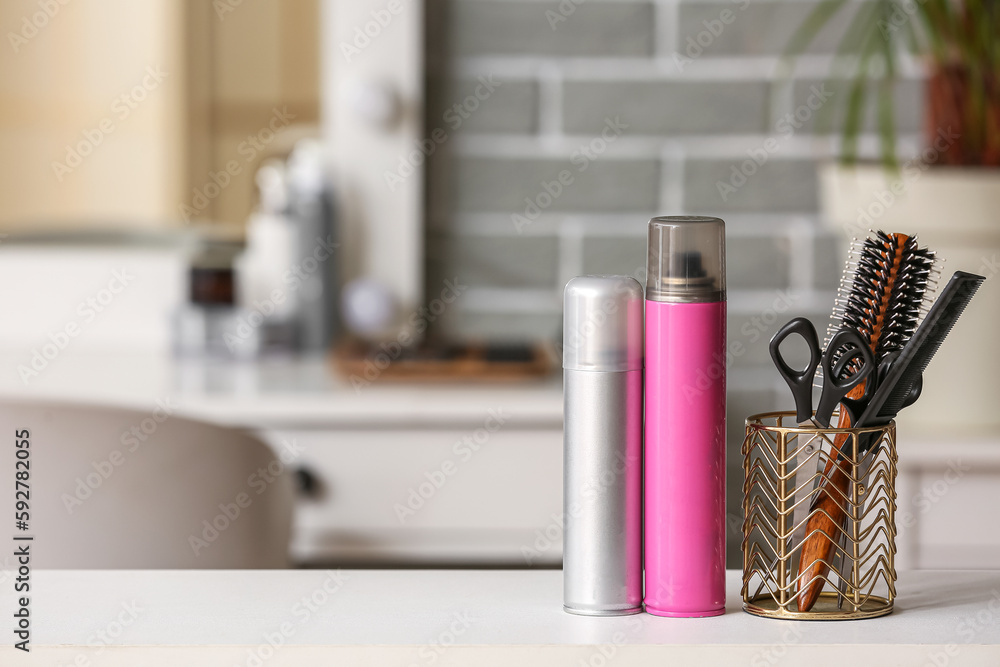 Different hair sprays and accessories on table in beauty salon