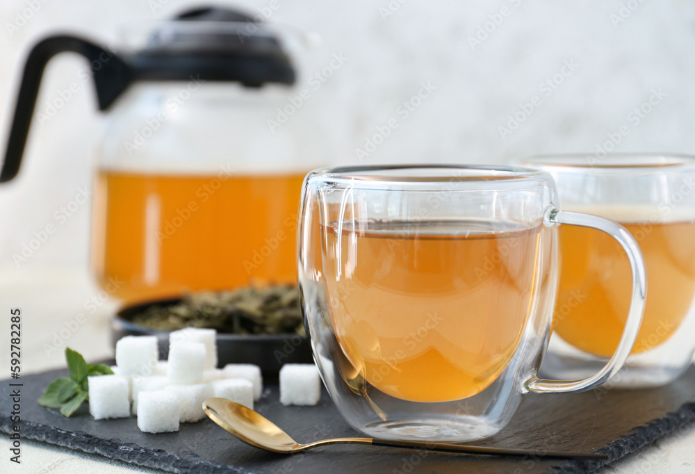 Cup of hot green tea on light background