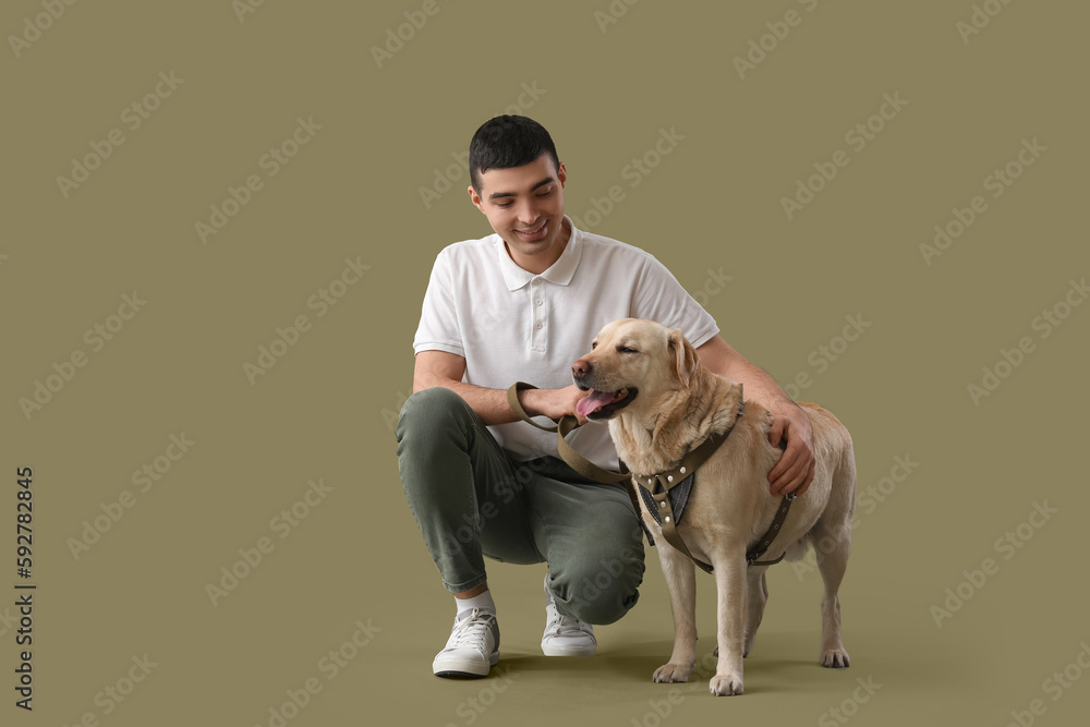 Young man with cute Labrador dog on green background