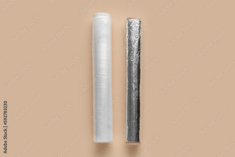 Rolls of aluminium foil and food film on color background