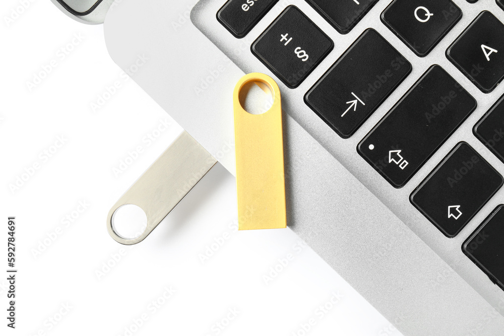 Modern laptop with metallic and golden USB flash drives isolated on white background