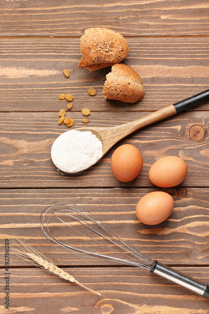 Composition with wheat flour, eggs, bread and utensils on wooden table