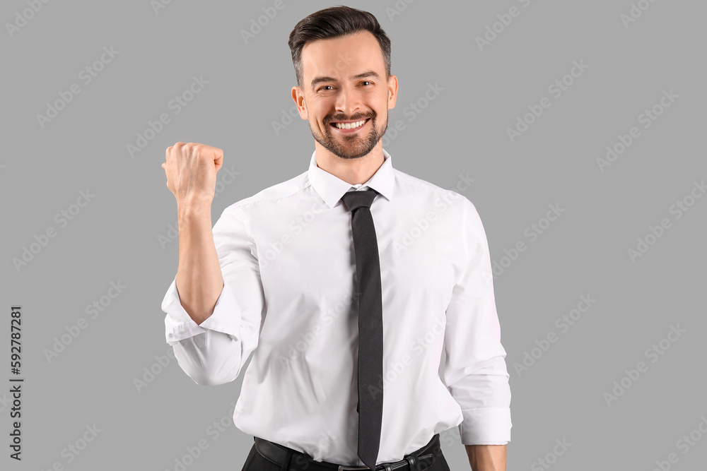 Handsome businessman pointing at something on grey background