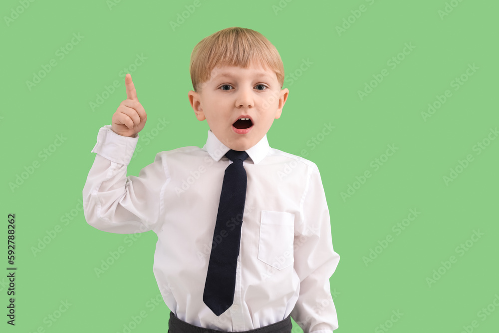 Funny little businessman pointing at something on green background