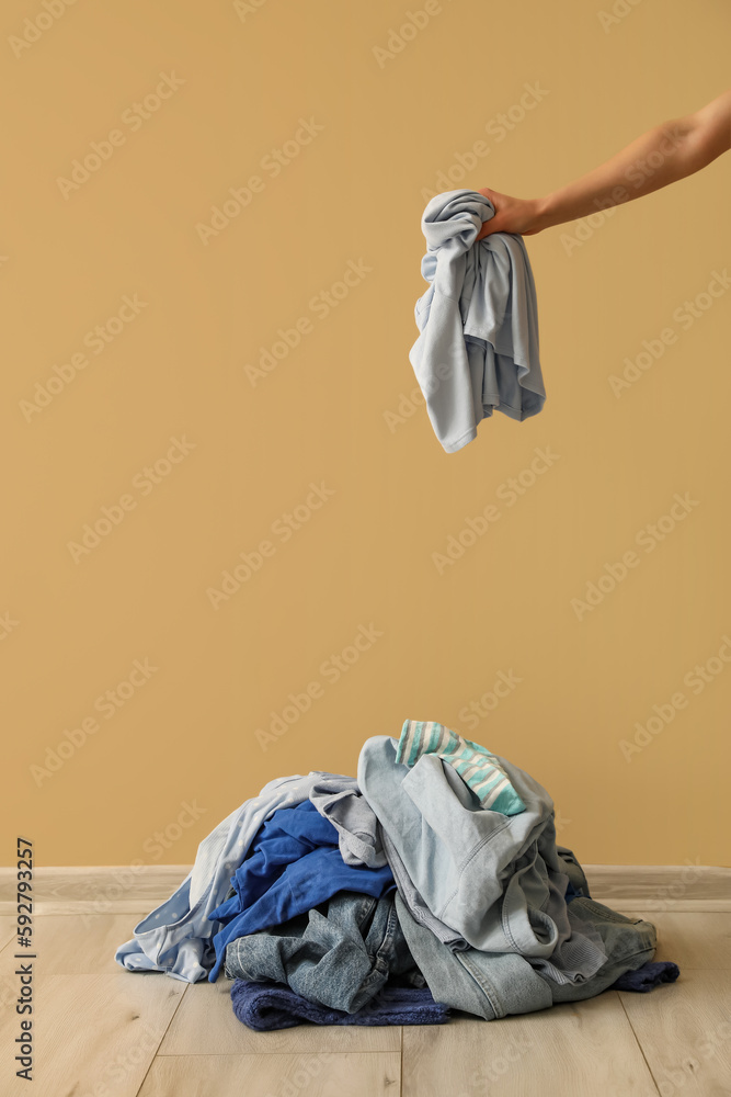 Woman with stack of dirty clothes near beige wall