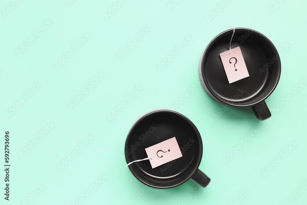 Cups with paper question marks on green background