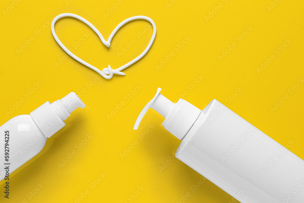 Sunscreen and heart made of cream on yellow background