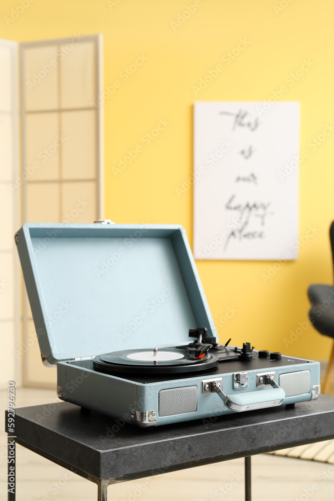 Record player with vinyl disk on table in room