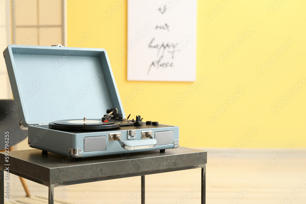 Record player with vinyl disk on table in room