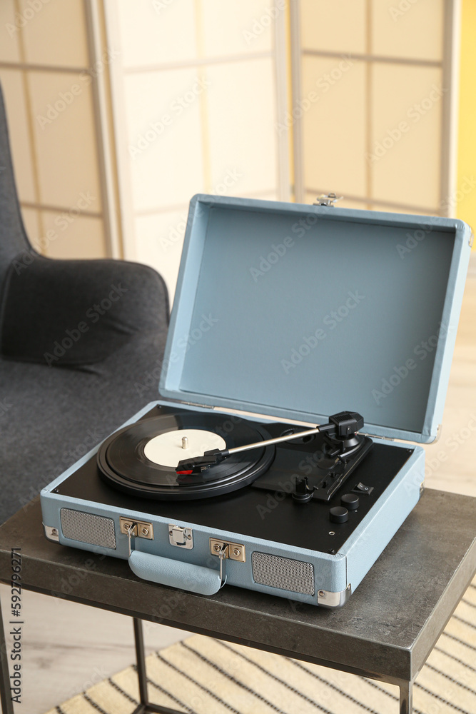 Record player with vinyl disk on table in room