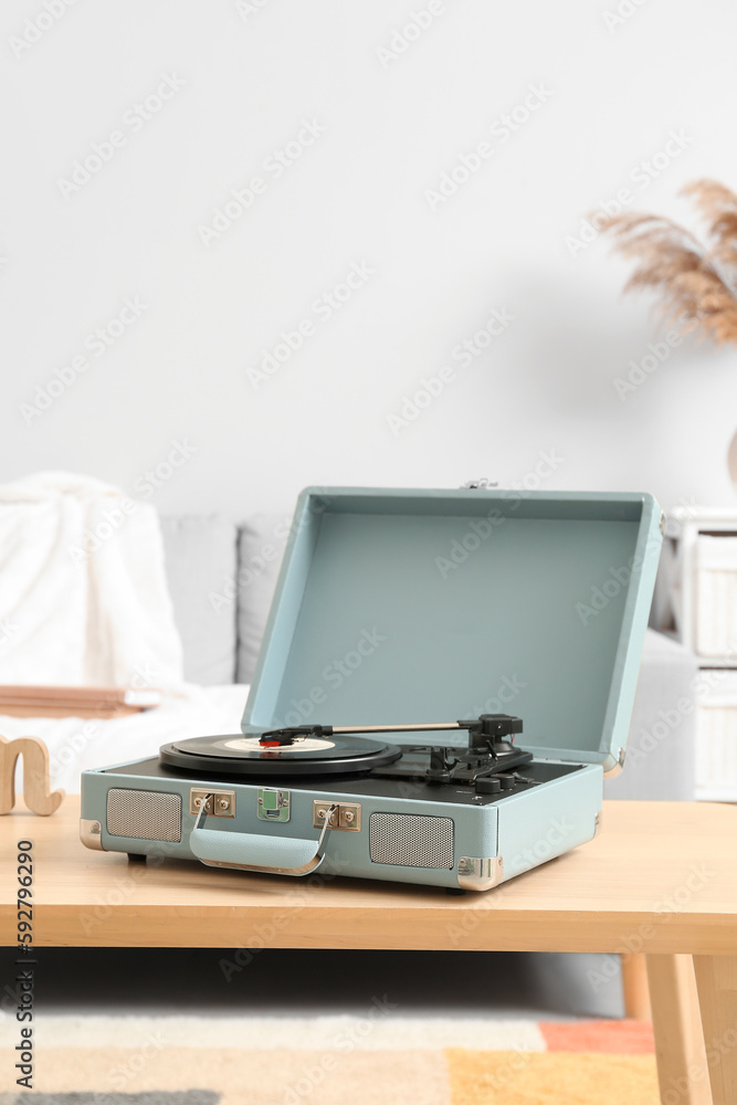 Record player with vinyl disk on table in room