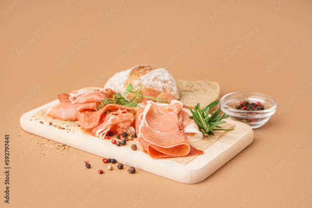 Wooden board with slices of tasty jamon on beige background