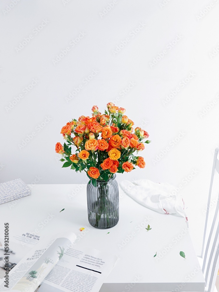 Vertical shot of a beautiful bouquet of roses in a blue glass vase on a white table with a magazine